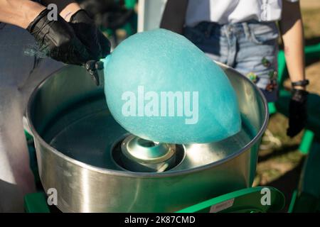 Cotton candy outside. Blue cotton candy on stick. Sugar product. Delicious food. Details of preparing treat. Stock Photo