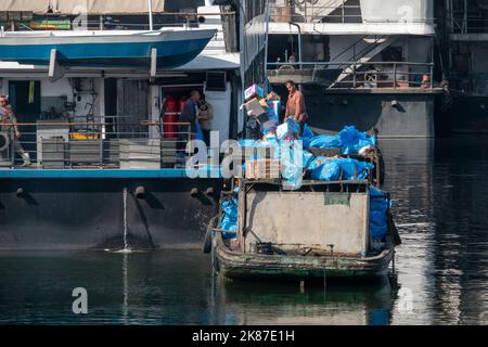 A garbage disposal barge for Nile cruise boats with men offloading blue bags Stock Photo