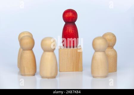 Red wooden people figure on top of wooden cube leading the rest of the followers. Stock Photo