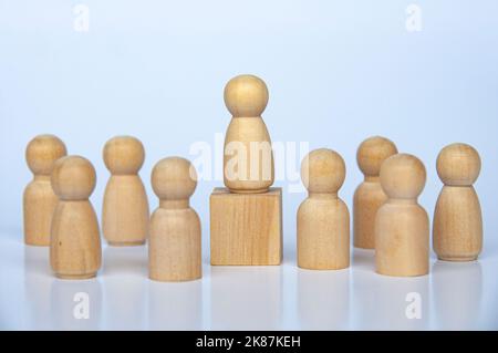 Wooden people figure on top of wooden cube leading the rest of the followers. Stock Photo