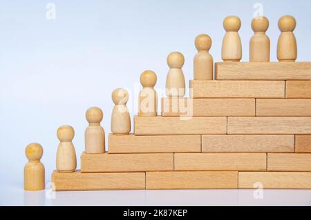 Wooden people figure on top of wooden blocks. Goal achievement, business growth and career progression. Stock Photo