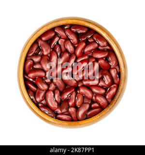 Red kidney beans, in a wooden bowl. Dried common kidney beans, a variety of the common bean, Phaseolus vulgaris. Vegetarian staple food. Stock Photo