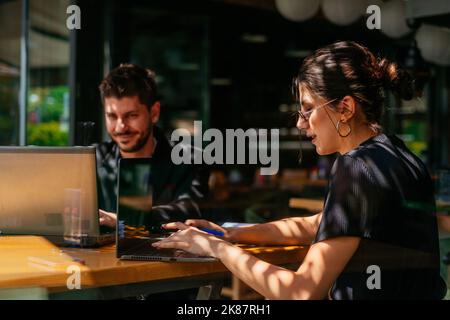 Two business guys are working on their business project seriously, online, in a cafe bar, on a beautiful day Stock Photo