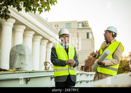Two senior construction managers are standing and talking about the company Stock Photo