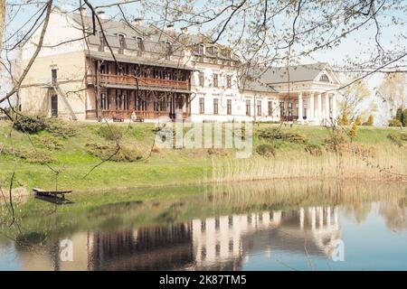 Belarus, village Radzivilki, 01.05.22. Restored old manor Svyatsk Gkursky in Belarus. View to main entrance with columns on bank of small pond with Stock Photo