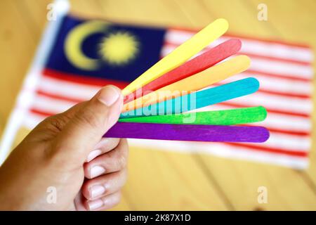A man holding multi-colored counting sticks for children on a background of Malaysia flag Stock Photo