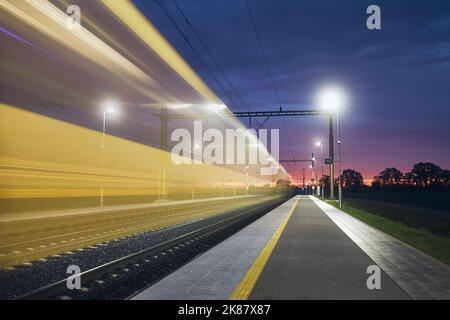 Modern railway at beautiful dawn. Light trail of high speed train on railroad track. Moving modern intercity passenger train. Stock Photo