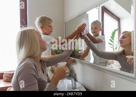 mother and son do cleaning together and clean the bathroom mirror Stock Photo