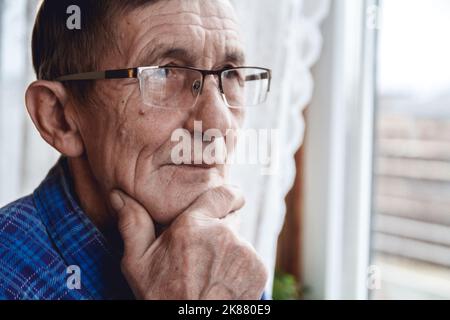 Senior standing at the window and thinking about something or fo Stock Photo