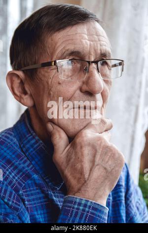Senior standing at the window and thinking about something or fo Stock Photo