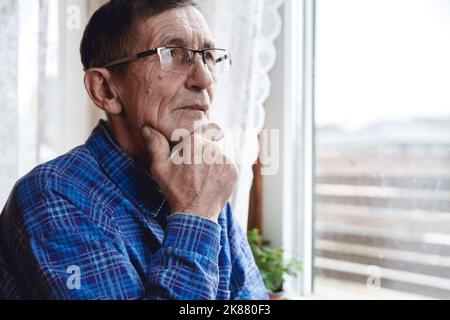 Senior standing at the window and thinking about something or fo Stock Photo