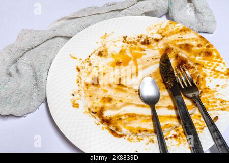Empty plate, dirty after the meal is finished. With fork and spoon in the kitchen. Stock Photo