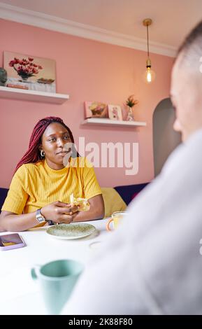 Young woman eating croissant at breakfast Stock Photo