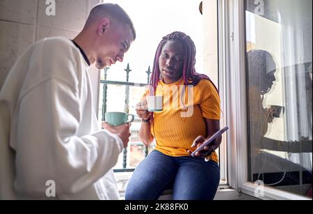Happy multi-ethnic couple having coffee using their mobile phones Stock Photo