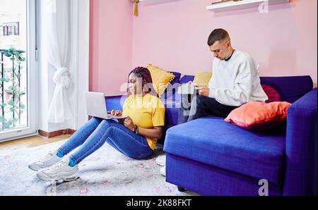 Multiracial couple of students preparing exams at home. Teamwork. Stock Photo