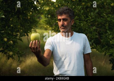 Portrait of a middle eastern holding an apple in his hand and posing in an apple orchard Stock Photo