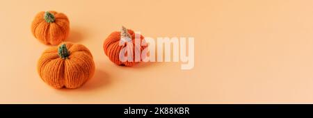 Knitted orange pumpkins on an orange background, autumn composition. Halloween concept. Stock Photo