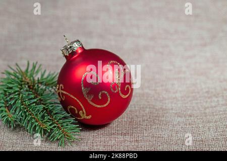 Red Christmas tree ball and spruce branch on jute fabric Stock Photo