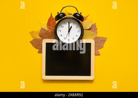 Autumn composition mockup banner with frame, dried leaves and black alarm clock on yellow background. Autumn, fall mock up Flat lay, top view, copy Stock Photo