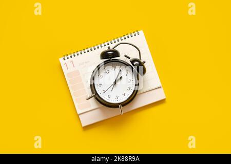 Autumn November Black Friday sale banner with calendar, black alarm clock, fall dried leaves and on yellow background. Autumn, fall Black Friday sale Stock Photo