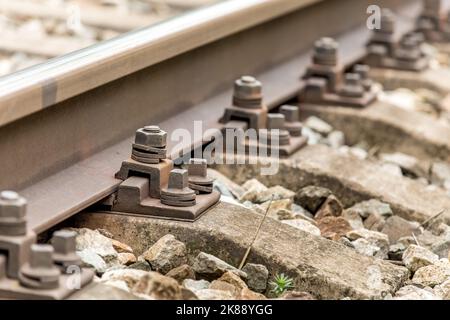 Railway track bolts. Detail of rusty screws and nut on railroad track. Rusty screws and nut on old railroad track. Concrete tie with rusty nuts and bo Stock Photo