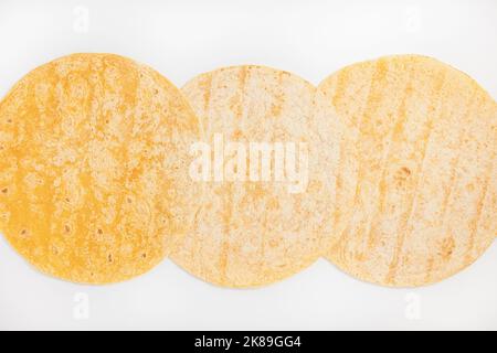 Tomato flavored wheat tortilla wraps. Spanish or Mexican circular unleavened flatbread from wheat flour. Ingredient for cooking fast food or snack. Closeup, white background Stock Photo
