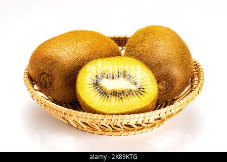 Whole and a half of ripe sweet organic hairy kiwi fruit or kiwifruit or chinese gooseberry in bamboo tray on white background. Stock Photo