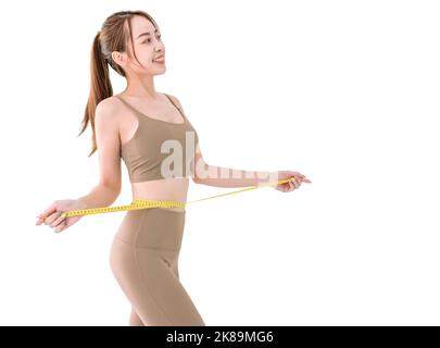 Young woman in sportswear measuring waist with tape Stock Photo