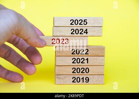 Hand pulling out year 2023 text on wooden blocks. Stock Photo