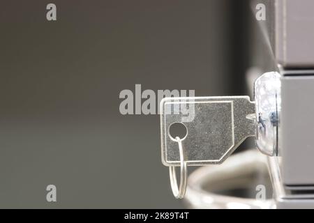 Generic key inserted in a filing cabinet lock. Side view closeup with copy space and selective focus. Stock Photo