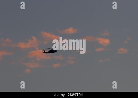 A silhouette of a Sikorsky SH-60 Seahawk helicopter with the United Stated Navy (USN flying in front of sunset clouds near NAF Atsugi airbase, Kanagaw Stock Photo