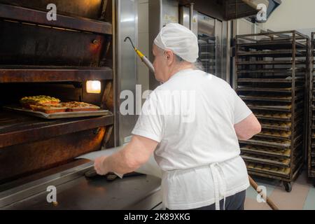 aged lady at work in big bakery restaurant Stock Photo