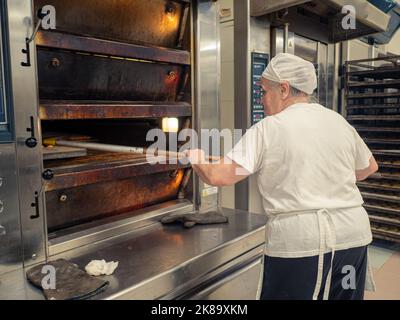 aged lady at work in big bakery restaurant Stock Photo