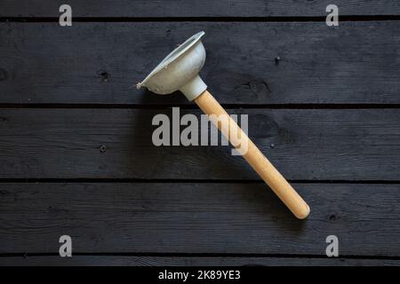 new rubber plunger on black wooden surface, plumber repair, toilet bowl cleaning Stock Photo