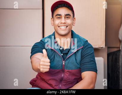 Delivery, thumbs up and courier man, shipping box and retail, ecommerce sales and service, employee smile in portrait. Success, worker in commercial Stock Photo