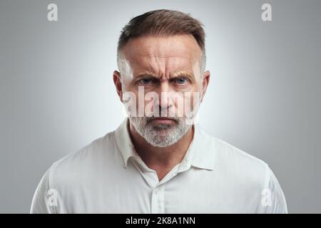 How could you do that. Studio portrait of a mature man looking angry against a grey background. Stock Photo