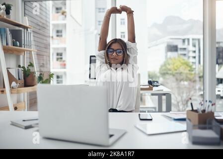 My back needed this. an attractive young businesswoman sitting alone in her office and stretching. Stock Photo