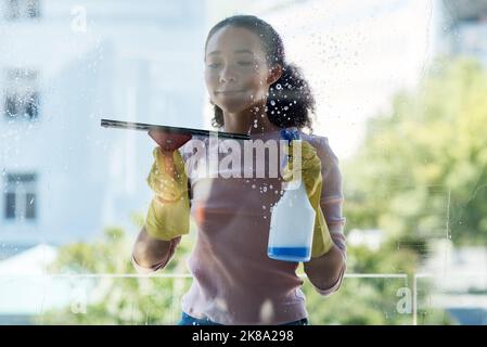 Time to walk into some windows. a young woman cleaning her window at home. Stock Photo