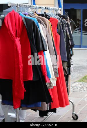 vintage used clothes and new dresses in the stall at the flea market Stock Photo