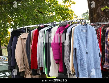 vintage used clothes and new dresses in the stall at the flea market Stock Photo