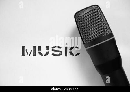 black microphone and the word music in block letters on a white background, music microphone, music, black and white photo, music theme Stock Photo