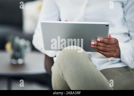 I carry my schedule everywhere. an unrecognizable businesswoman sitting alone and using a digital tablet to work from home. Stock Photo