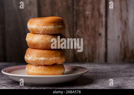 Glazed donuts, placed one on top of the other on a plate. Stock Photo
