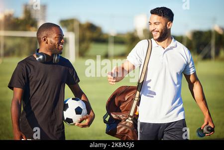 Soccer players, friends and men walking on football field after practice or fitness training on grass field. Diversity, smile and football players Stock Photo