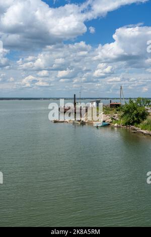 small rusty pier on summer day with white fluuffy cloudscape over it Stock Photo
