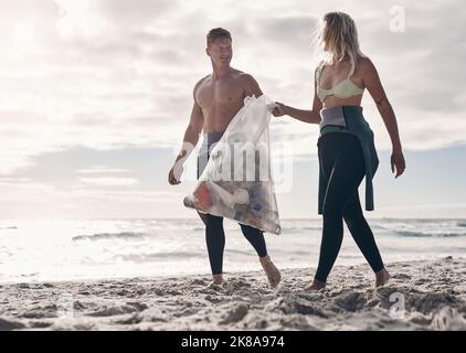 We rely on the tides and the tides rely on us. a young couple doing a beach clean while wearing wetsuits. Stock Photo