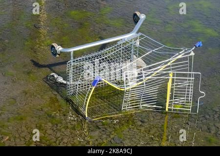 a broken supermarket trolley is lying on the street in a puddle. High quality photo Stock Photo