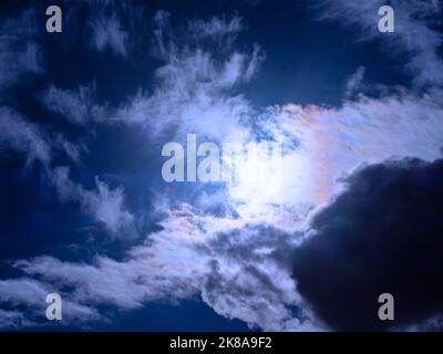 The sun shines through overcast dark-blue storm clouds Stock Photo