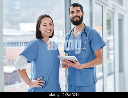 Improving health outcomes together. Portrait of two medical practitioners using a digital tablet together in a hospital. Stock Photo