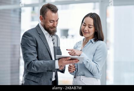 Brainstorming in their quest to innovate. two businesspeople using a digital tablet together in an office. Stock Photo